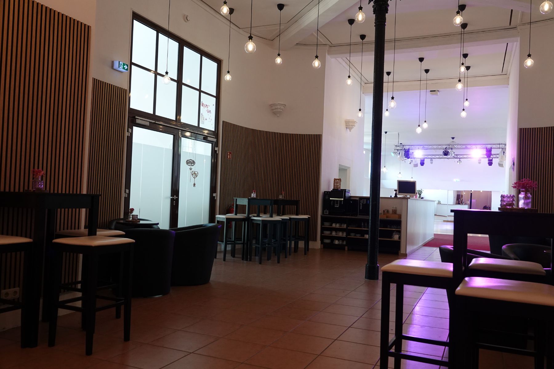 Einladender Empfangsbereich im Marstall Gotha mit stilvoller Lounge, die zum Verweilen einlädt. Premium Kaffee und ein Wasserspender stehen den Gästen zur Verfügung, um Komfort und Wohlbefinden bei Veranstaltungen zu gewährleisten.